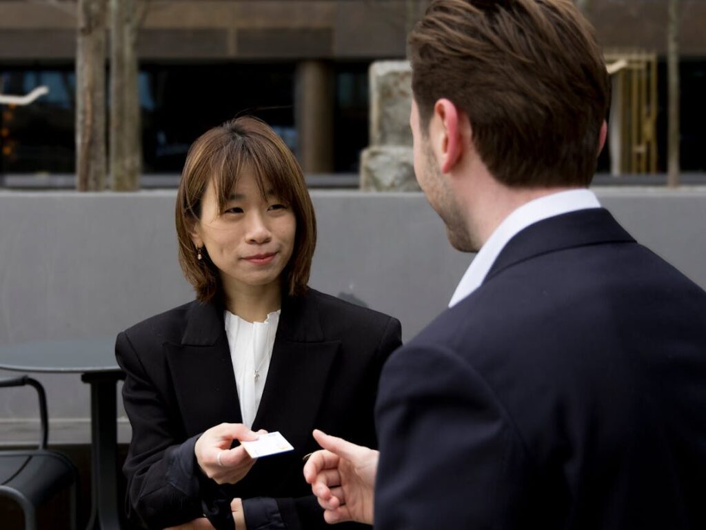 Two business professionals having a meeting outdoors, exchanging business cards.